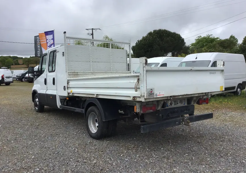IVECO Daily Chassis double cabine blanc vu en 3/4 arrière droit avec benne et roues jumelées sur parking.