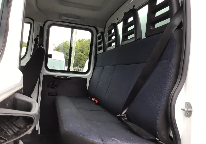 Vue intérieure de la cabine arrière du Daily Iveco blanc, montrant la banquette noire avec ceintures de sécurité.