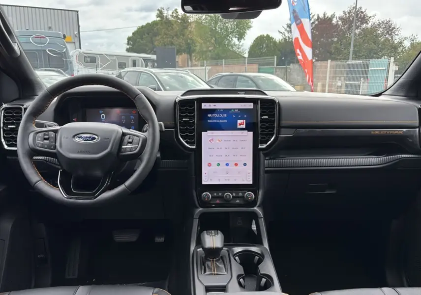 Intérieur du Ford Ranger 2025 Wildtrak Plus noir agate, vue frontale du tableau de bord avec écran tactile vertical et volant cuir.