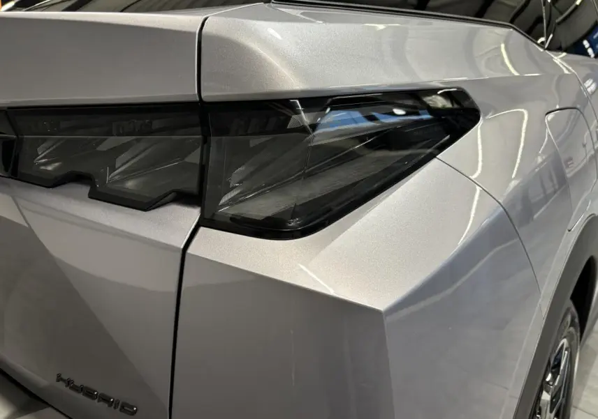 Gros plan sur le feu arrière droit du Peugeot 3008 gris Artense avec bandeau noir laqué et monogramme Hybrid.