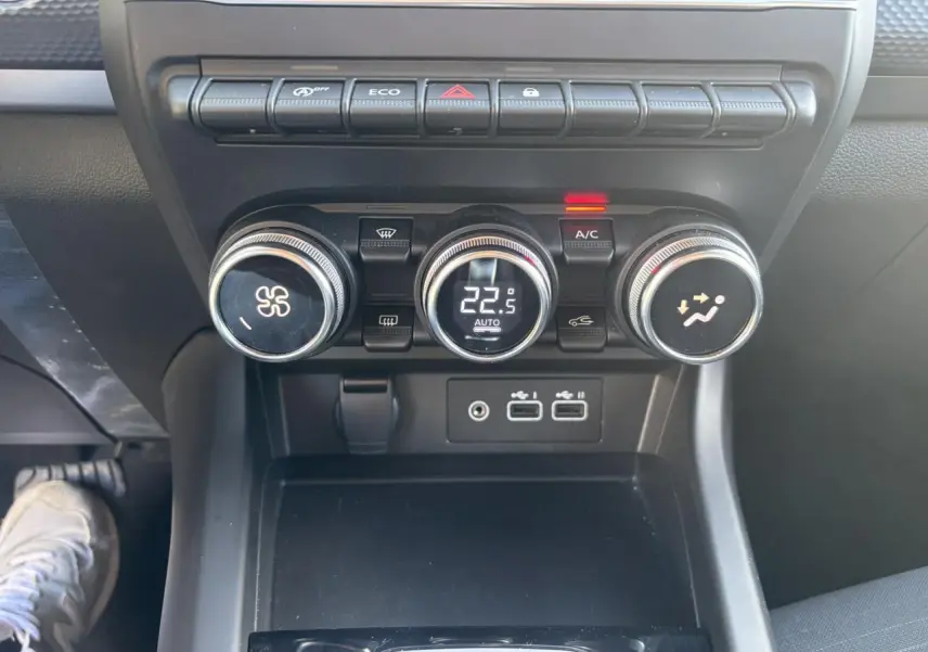 Gros plan sur la console centrale noire de la Renault Arkana 2025, montrant les commandes de climatisation et ports USB.