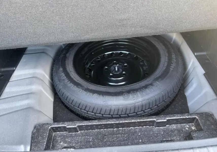 Vue rapprochée de la roue de secours temporaire noire dans le coffre d'un Renault Arkana gris métallisé.