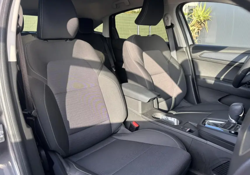 Vue intérieure côté droit montrant les sièges tissu noirs et l'accoudoir central du Renault Arkana gris métallique 2025.