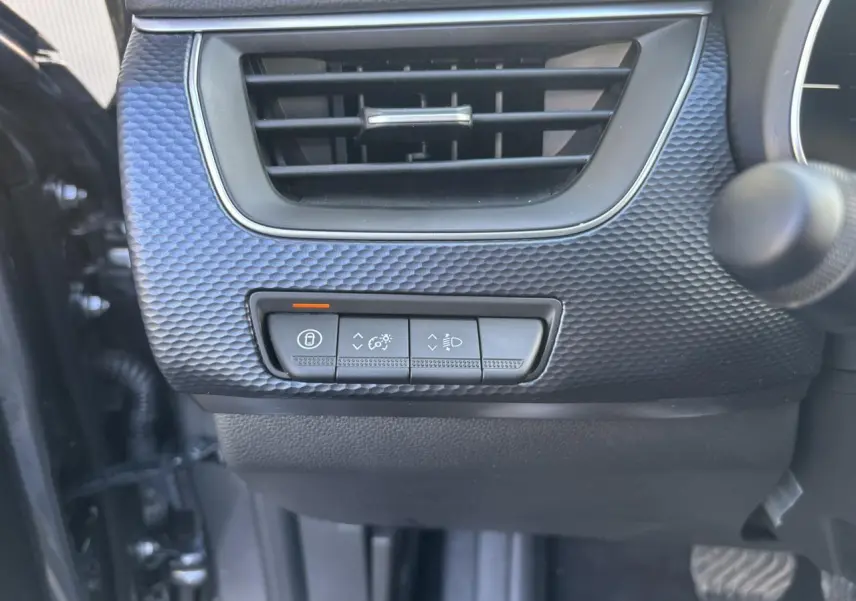 Détail des commandes d’éclairage et verrouillage sous la grille d’aération, intérieur gris du Renault Arkana 2025.