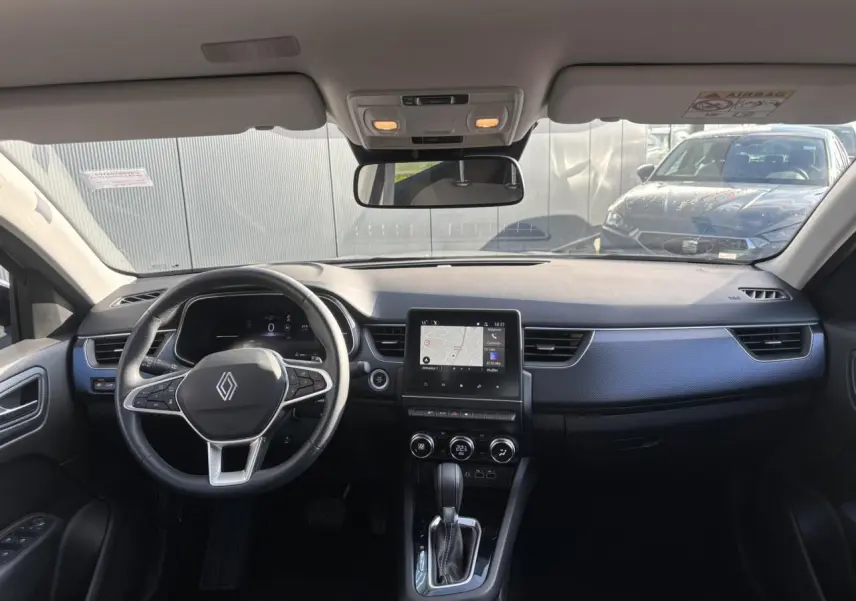Vue intérieure avant du Renault Arkana gris métallique 2025, avec tableau de bord numérique et écran GPS tactile central.