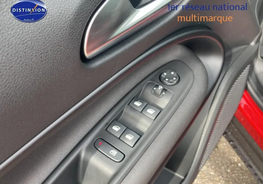 Gros plan sur la commande des vitres côté conducteur de l'Alfa Romeo Junior rouge, avec poignée intérieure et haut-parleur.