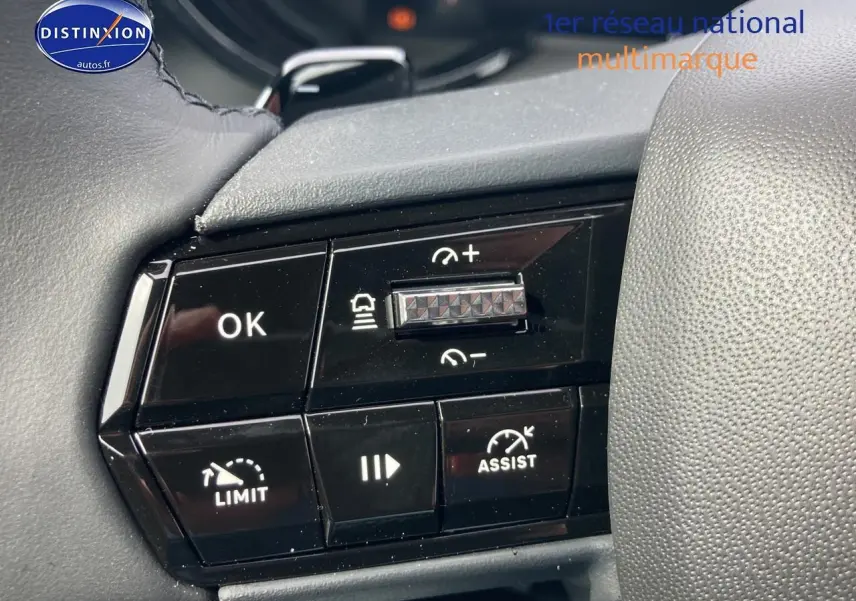 Gros plan sur les commandes au volant noir de l'Alfa Romeo Junior 1.2 hybride, avec boutons de régulateur et assistance.