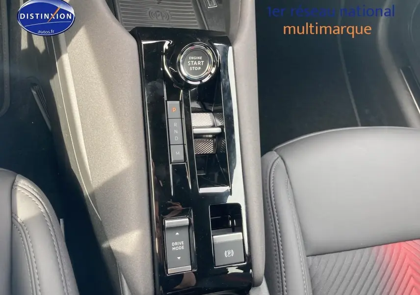 Vue rapprochée de la console centrale noire brillante de l'Alfa Romeo Junior 1.2 hybride, avec siège cuir noir partiel visible.