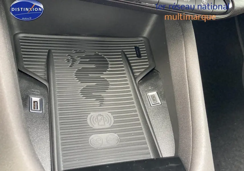 Gros plan sur le chargeur à induction noir avec logo serpent Alfa Romeo, entouré de ports USB dans l'habitacle.