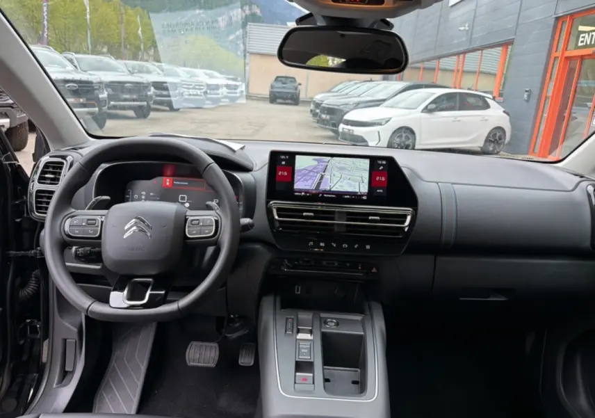 Vue intérieure avant du Citroën C5 Aircross noir 2025, tableau de bord moderne avec écran tactile et volant multifonctions.