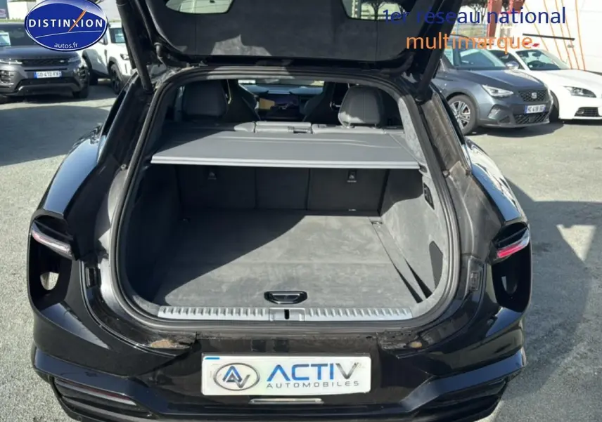 Coffre ouvert vu de l'arrière d'une Lotus Eletre noire 612ch électrique, montrant l'espace de chargement vide.