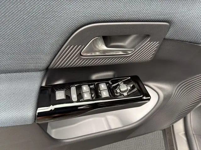 Gros plan sur la commande des vitres et rétroviseurs côté conducteur d'une Citroën C5 hybride gris foncé, intérieur tissu et plastique.