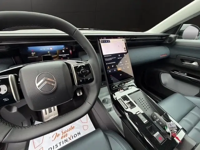 Intérieur de la Citroën C5 Hybride 2026, vue côté conducteur sur volant cuir et grand écran tactile central vertical.