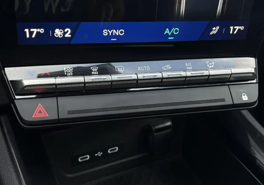 Gros plan sur la console centrale du Renault Austral E-Tech 2025, avec commandes climatisation et ports USB visibles.