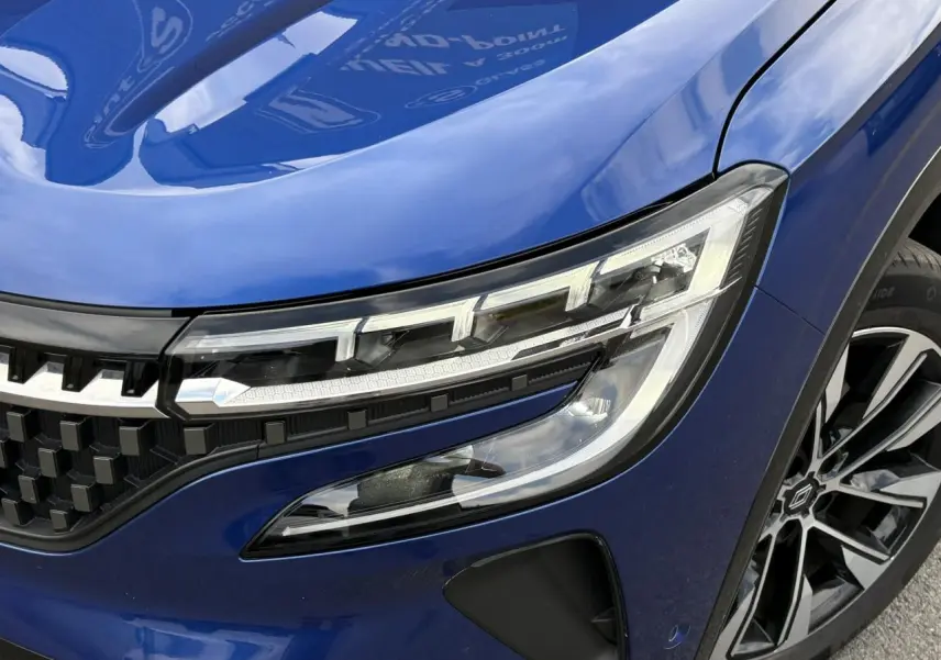 Gros plan sur l'avant droit du Renault Austral Bleu Iron, mettant en valeur le phare LED et la jante alliage noire diamantée.