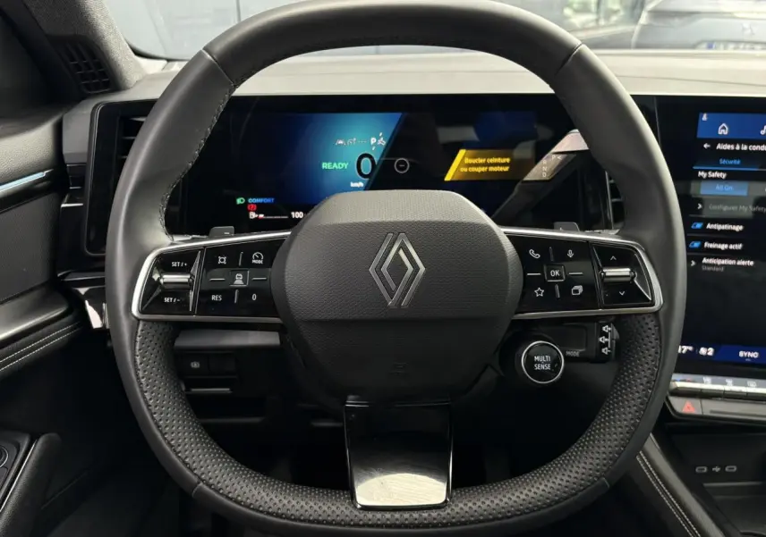 Vue frontale du volant noir texturé du Renault Austral 2025 avec tableau de bord numérique et écran tactile latéral.