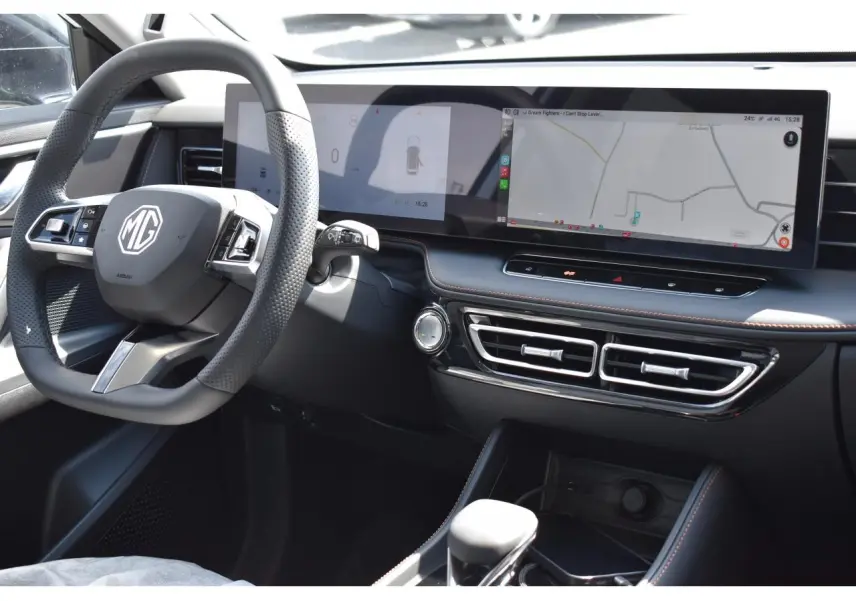 Vue intérieure côté conducteur du MG EHS blanc 2026, avec tableau de bord numérique large et volant multifonction.