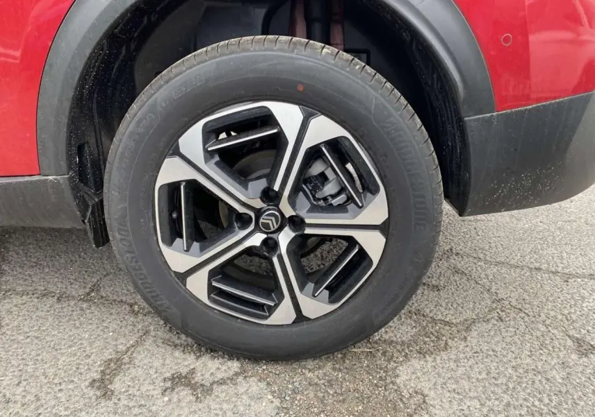 Gros plan sur la roue avant gauche avec jante alliage diamantée du Citroën C3 Aircross Rouge Elixir au toit noir.