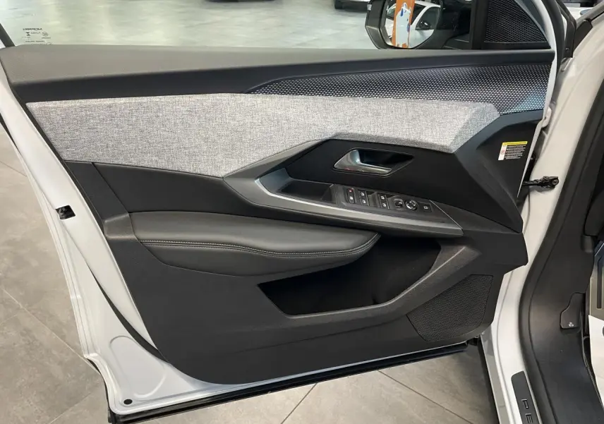 Vue intérieure de la porte avant gauche du Peugeot 3008 blanc Okenite avec habillage tissu gris et inserts noirs laqués.