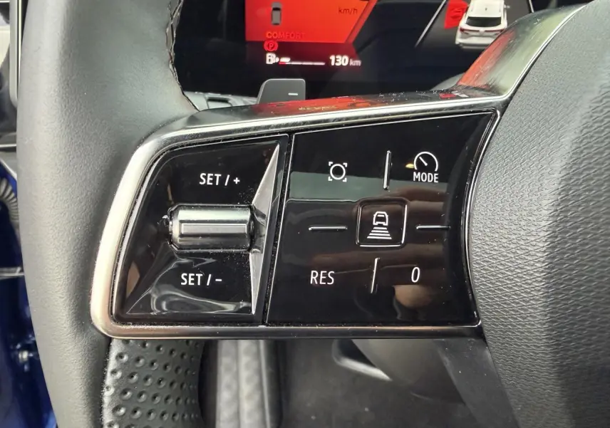 Gros plan sur les commandes à gauche du volant du Renault Austral bleu, affichage digital orange en arrière-plan.