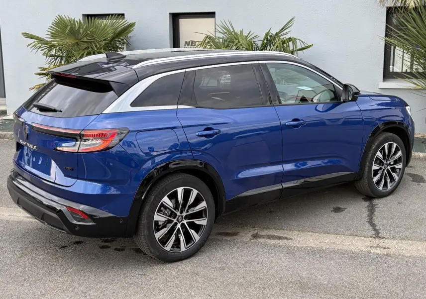 Vue 3/4 arrière droite du Renault Austral bleu Iron avec toit noir panoramique et jantes alliage noires diamantées.