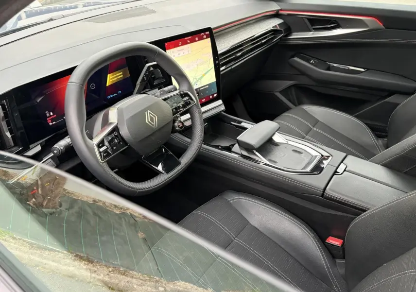 Vue intérieure côté conducteur du Renault Austral E-Tech 2025, avec tableau de bord numérique et écran tactile vertical.