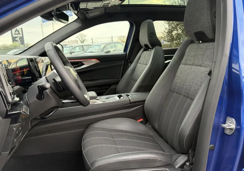 Vue intérieure côté conducteur du Renault Austral 2025 bleu Iron, avec sellerie mixte tissu et cuir gris et toit panoramique visible.