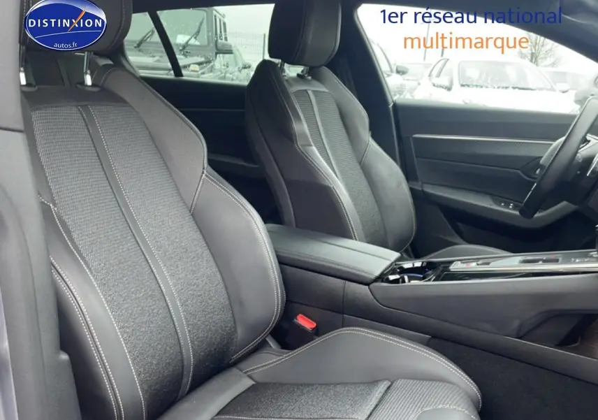 Vue intérieure côté gauche des sièges avant en tissu et cuir noir avec surpiqûres blanches d’un Peugeot 508 SW gris Artense 2024.