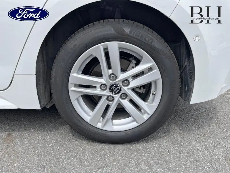 Gros plan sur la roue avant droite d'une Toyota Corolla blanche avec jante alliage et logo Toyota au centre.