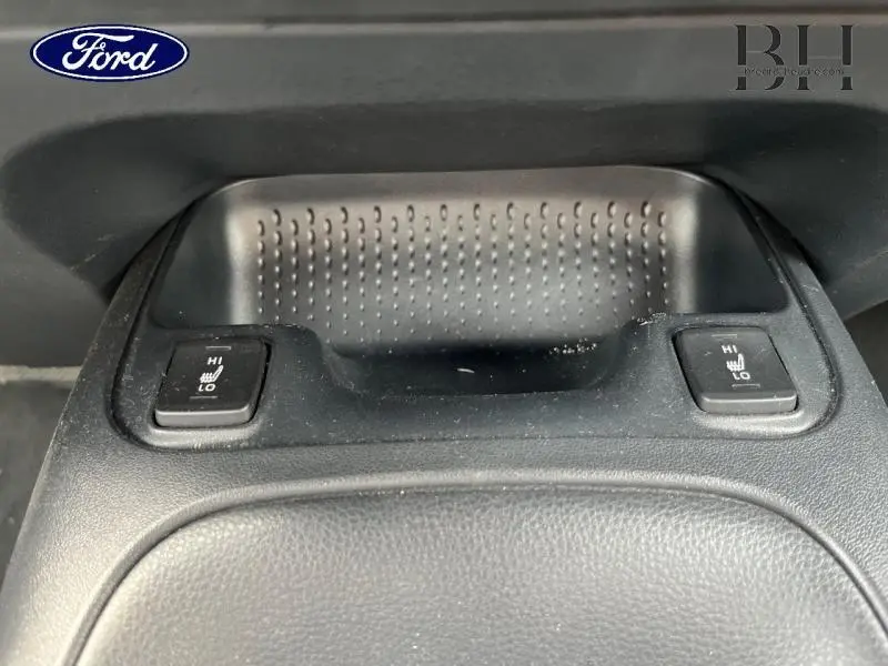 Gros plan sur les commandes de sièges chauffants avant dans l'habitacle noir d'une Toyota Corolla blanche.