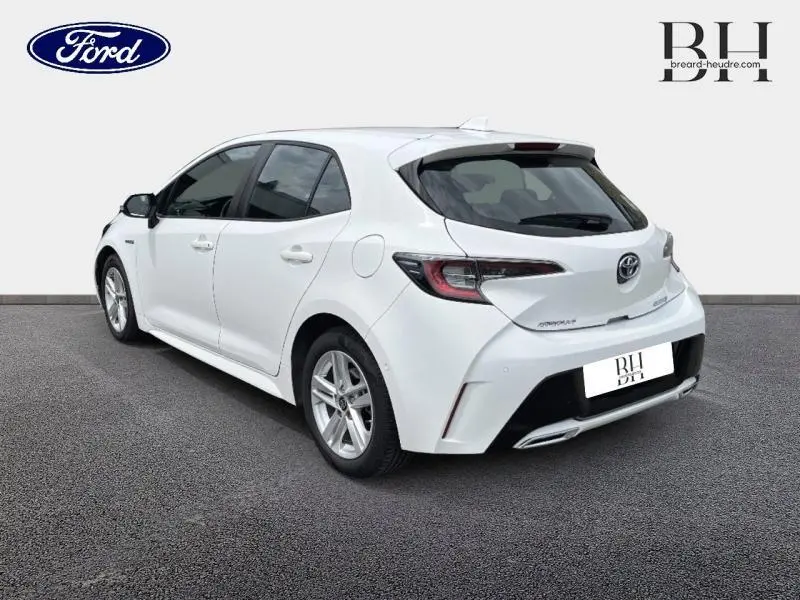 Vue 3/4 arrière droite d'une Toyota Corolla blanche avec feux arrière LED et double sortie d'échappement chromée.