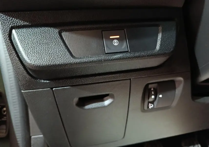 Détail intérieur montrant le bouton de condamnation centralisée et réglage des phares sur la planche de bord côté conducteur.