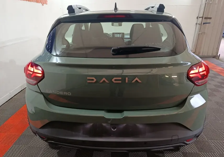 Vue arrière d'une Dacia Sandero Extreme+ TCe 110 2024 en vert avec feux LED allumés et barres de toit noires.