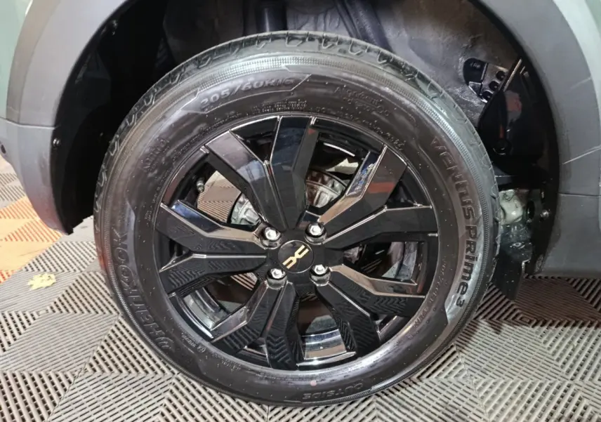 Gros plan sur la roue avant droite noire brillante du Dacia Sandero Extreme+ TCe 110 vert 2024 avec jante en alliage.