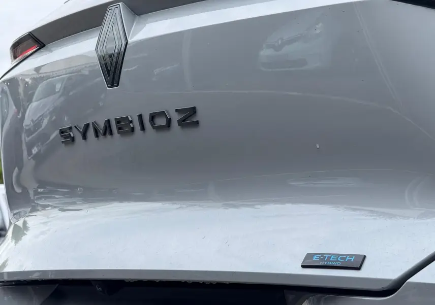 Gros plan arrière du Renault Symbioz gris Rafale avec logo et badge E-TECH Hybrid visibles sur le coffre.