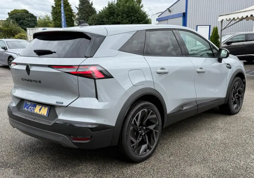 Vue 3/4 arrière droit d'une Renault Symbioz gris rafale avec jantes noires et feux arrière LED distinctifs.