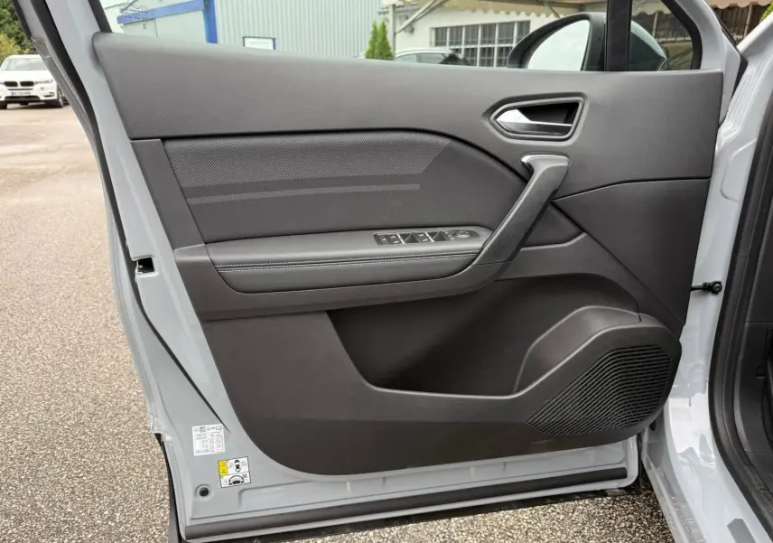 Vue intérieure de la porte avant gauche gris rafale du Renault Symbioz 2026 avec commandes de vitres et haut-parleur intégré.