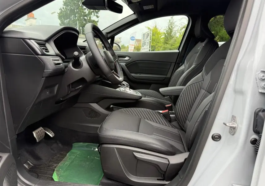 Vue intérieure côté conducteur de la Renault Symbioz 2026, sièges noirs avec surpiqûres et volant multifonction.