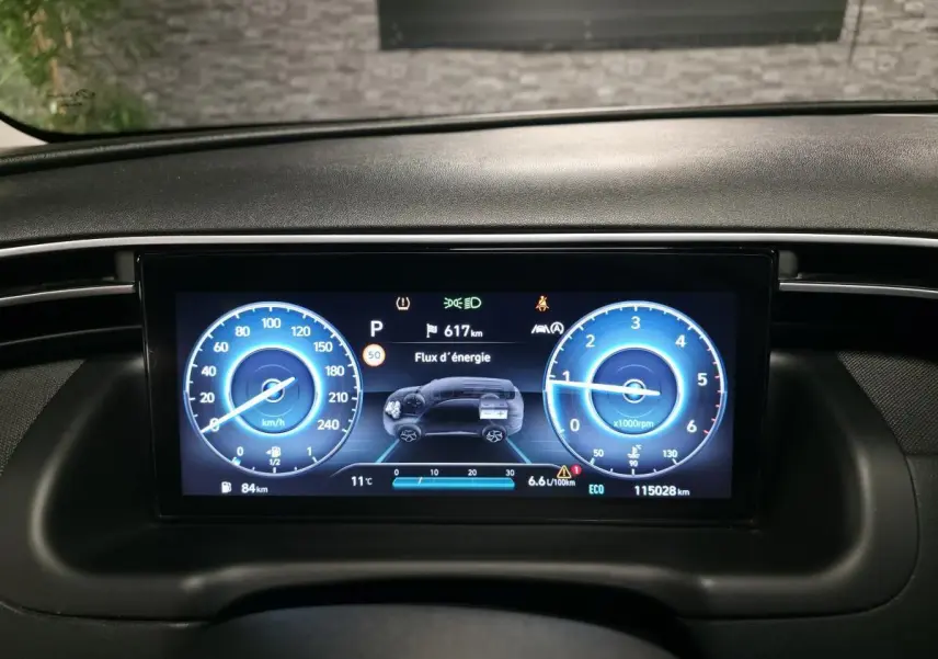 Tableau de bord numérique du Hyundai Tucson 2020, affichage bleu avec vitesse, régime et flux d'énergie.