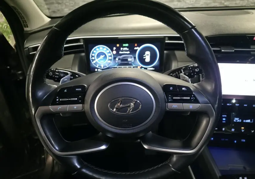Vue rapprochée du volant cuir noir du Hyundai Tucson 2020 avec tableau de bord numérique et commandes intégrées.