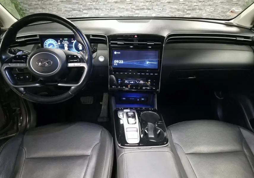 Vue intérieure avant du Hyundai Tucson 2020, tableau de bord noir avec écran tactile central et volant multifonction cuir.