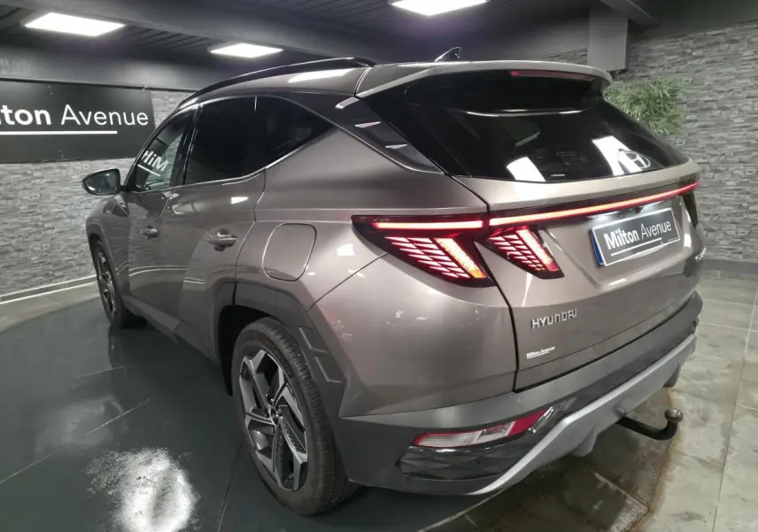 Vue 3/4 arrière droite d’un Hyundai Tucson gris métallisé avec feux arrière LED et jantes alliage 19 pouces.