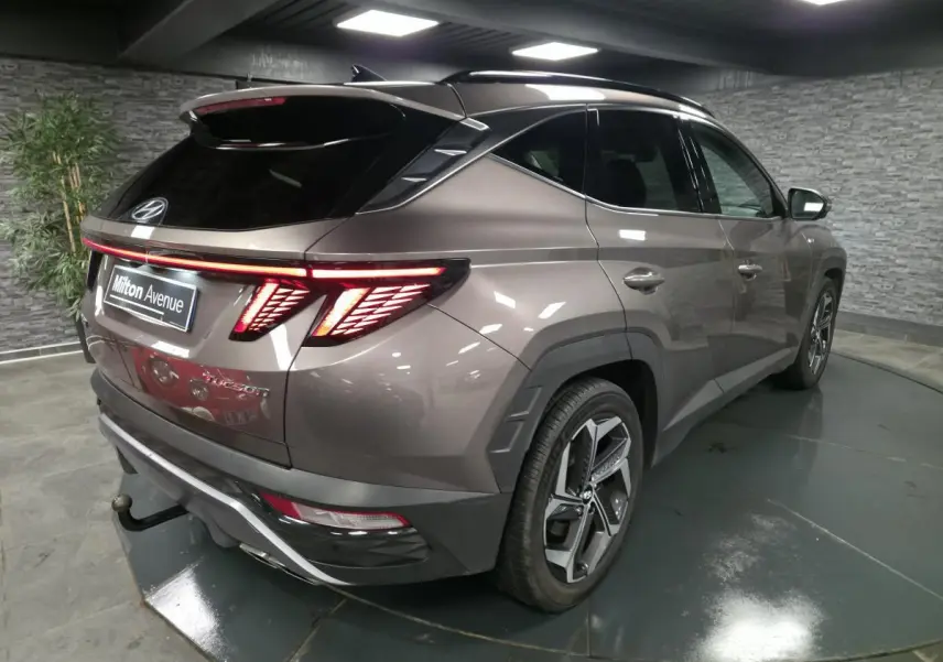 Vue 3/4 arrière droite du Hyundai Tucson gris métallisé avec feux arrière LED et jantes alliage 19 pouces.