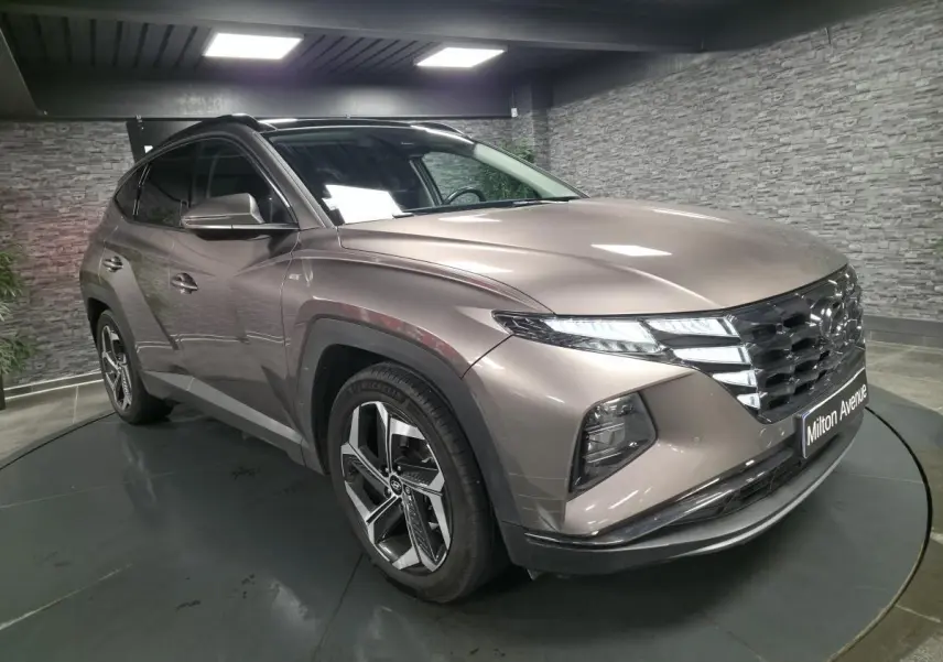 Vue 3/4 avant droit du Hyundai Tucson gris métallisé avec calandre chromée et jantes alliage 19 pouces.