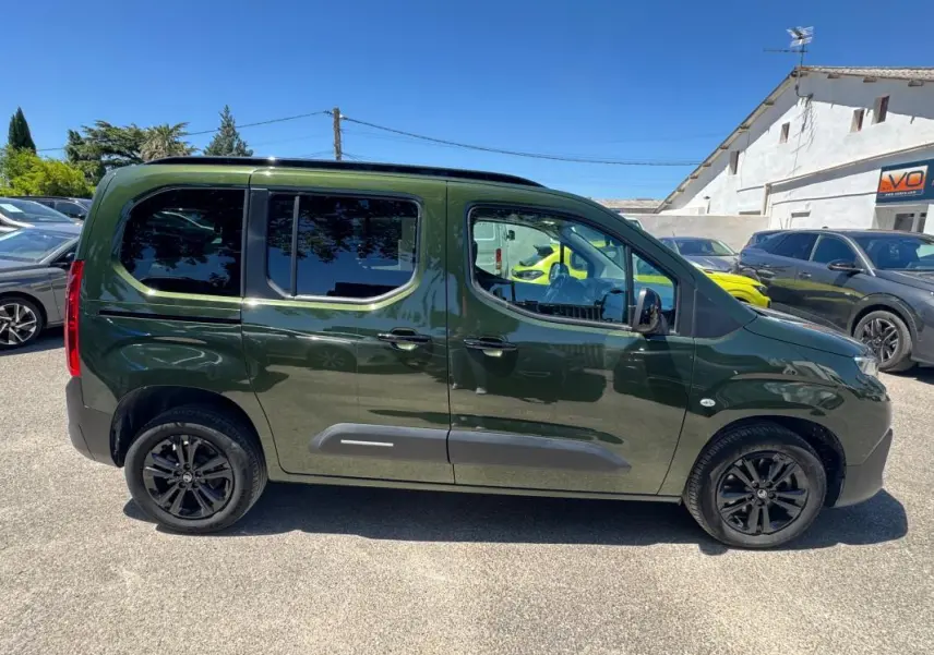 Vue de profil côté droit du Citroën Berlingo vert foncé 2024 avec barres de toit et jantes noires.