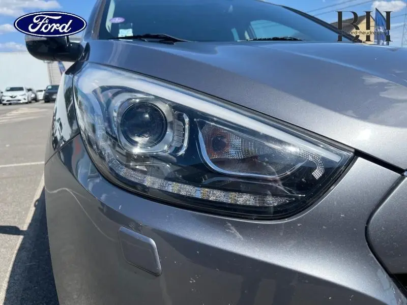 Gros plan sur le phare avant droit d’un Hyundai ix35 2014 gris acier, soulignant le design moderne et les détails lumineux.