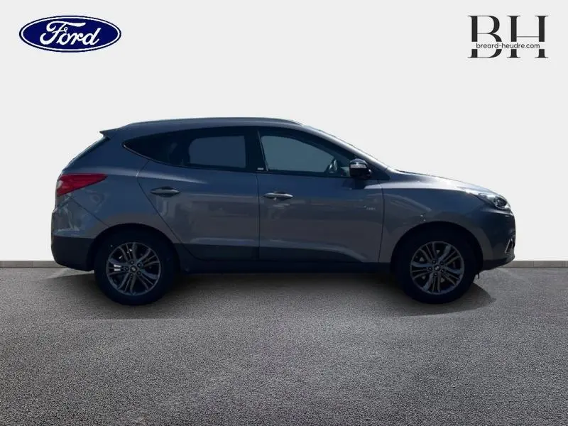 Profil côté gauche d'un Hyundai ix35 gris acier 2014 avec jantes alliage et vitres teintées sur fond neutre.