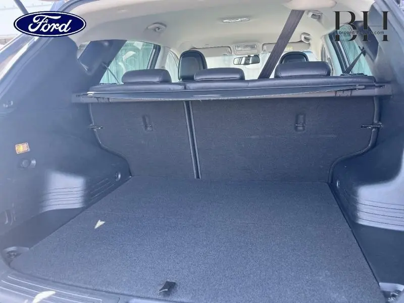 Vue du coffre arrière ouvert d'un Hyundai ix35 2014 gris Steel Grey, montrant la tablette cache-bagages et la banquette arrière.