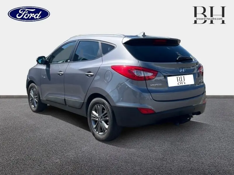 Vue 3/4 arrière droite d'un Hyundai ix35 2014 gris Steel Grey avec jantes alu et becquet arrière.