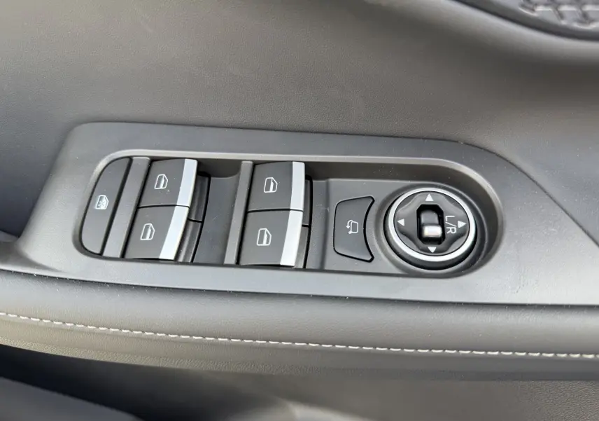 Gros plan sur les commandes de lève-vitres et réglage des rétroviseurs côté conducteur du JAECOO J5 gris Phantom.